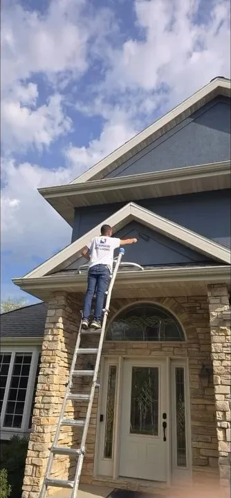 Roll n' Brush painter on a ladder painting a stucco gable